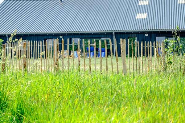 Kastanjehouten hek langs het grasveld bij de zwemvijver